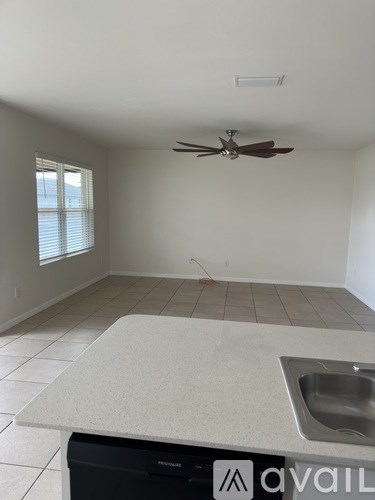 A kitchen with a fan on the ceiling and a sink in the counter.