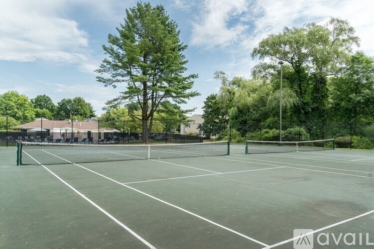 A tennis court surrounded by trees and a fence.