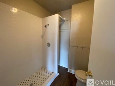 A bathroom with a toilet, shower, and sink.