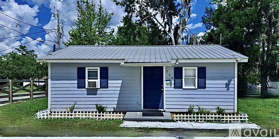 A small blue house with a metal roof and a white picket fence.