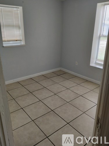 A room with tiled flooring and a window with blinds.