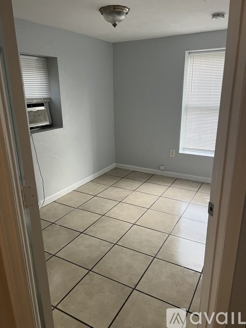 A room with tiled flooring and a window with blinds.