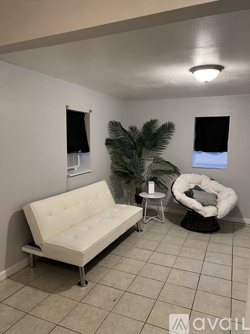 A white couch sits in a room with a plant and a chair.