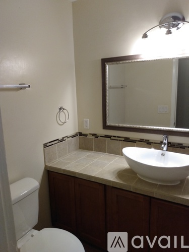 A bathroom with a toilet, sink, and mirror.