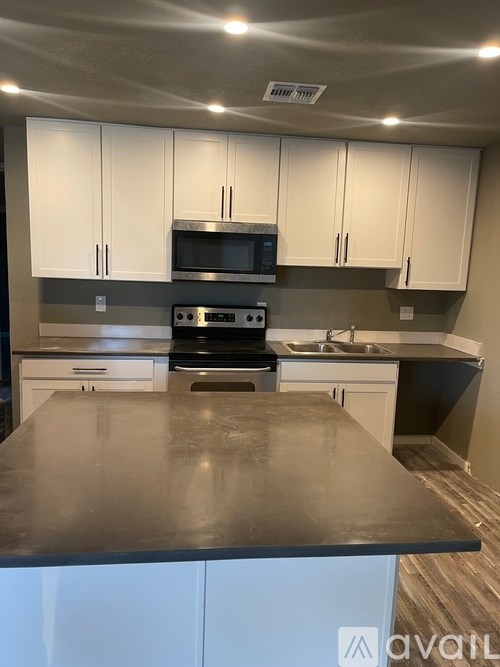 A kitchen with a black countertop and white cabinets.