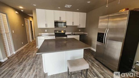 A kitchen with a stainless steel refrigerator and a table with a bench.