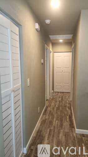 A hallway with a white door and wooden flooring.