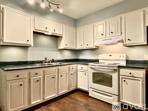 A kitchen with white cabinets and a black countertop.