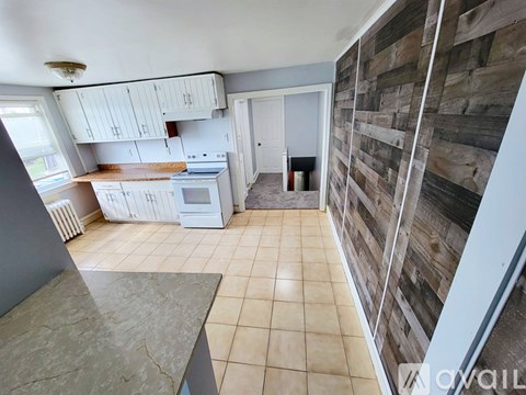 A kitchen with white cabinets and a wooden wall panel.