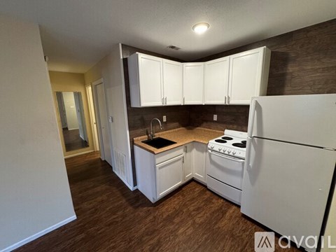 A kitchen with white appliances and wooden floors.