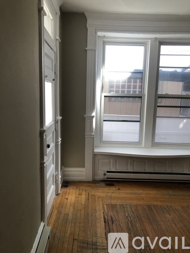 A room with a window and a wooden floor.