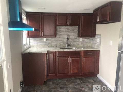 A kitchen with brown cabinets and a stone backsplash.