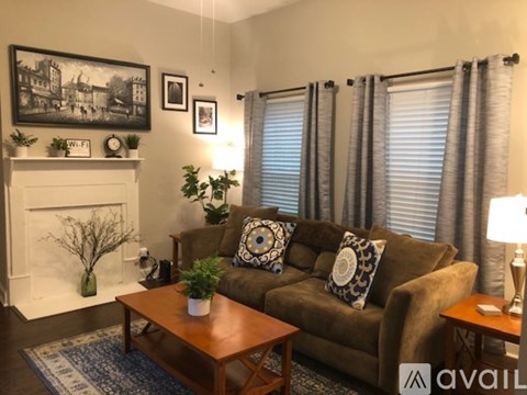 A living room with a brown couch, a fireplace, and a painting on the wall.