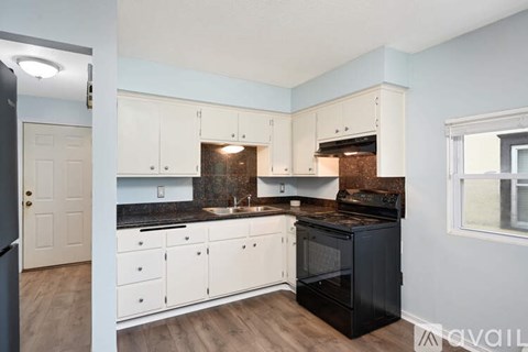 A kitchen with white cabinets and a black oven.