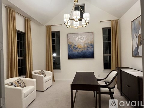 A living room with a brown table, two chairs, a couch, and a painting on the wall.