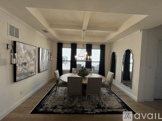 A dining room with a table set for four and a chandelier hanging from the ceiling.