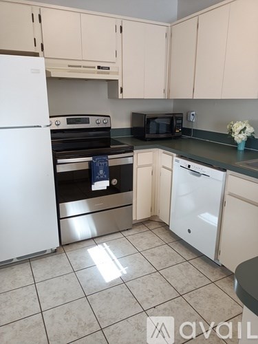 A kitchen with white appliances and a black counter.