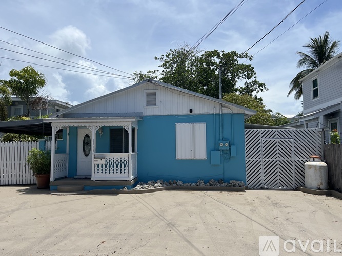 A blue house with a white porch and a white fence.