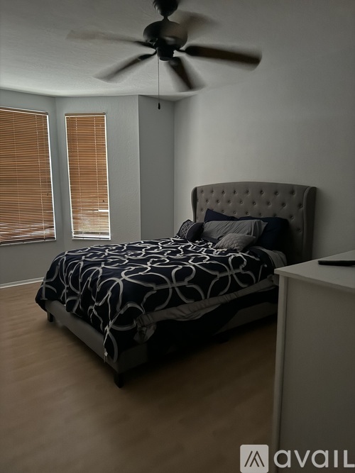 A bedroom with a bed, a ceiling fan, and a window with blinds.