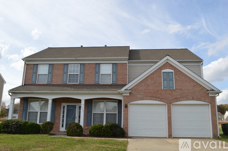 A two-story house with a brick facade and white garage doors.