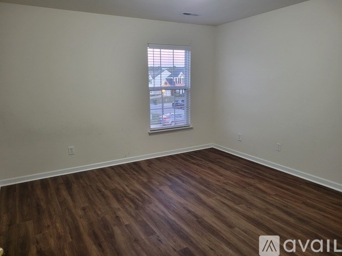 A room with wooden flooring and a window showing a street view.