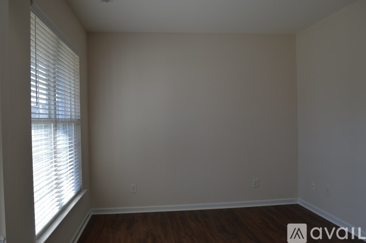 A room with a window and wooden floors is available for rent.