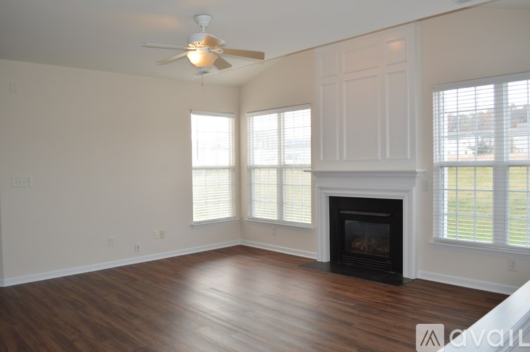A living room with a fireplace and a ceiling fan.