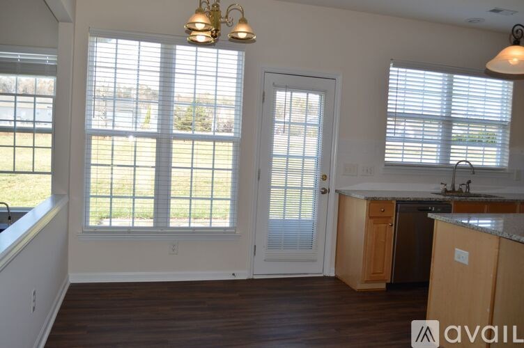 A kitchen with wooden cabinets and a large window with blinds.