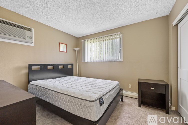 A bedroom with a bed, nightstand, and window.