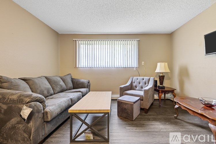 A living room with a grey couch, a wooden coffee table, and a grey armchair.