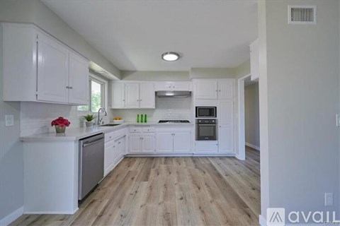 A kitchen with white cabinets and a wooden floor.