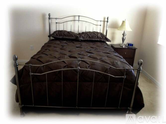 A bed with a brown comforter and a metal frame.