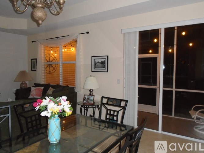 A living room with a glass table and a vase of flowers on it.