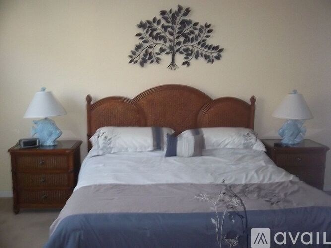 A bed with a wooden headboard and a blue blanket is in the foreground with two lamps on either side.