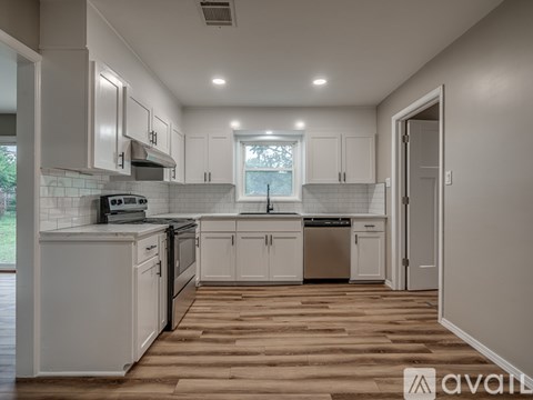A kitchen with white cabinets and a wooden floor.