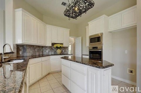 A kitchen with white cabinets and a granite countertop.