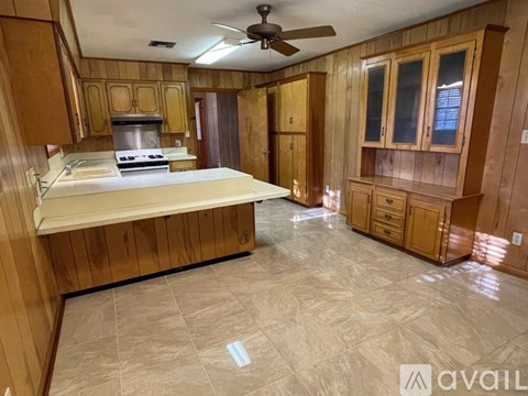 A kitchen with wooden cabinets and a marble floor.