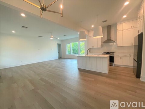 A spacious kitchen with white cabinets and a wooden floor.