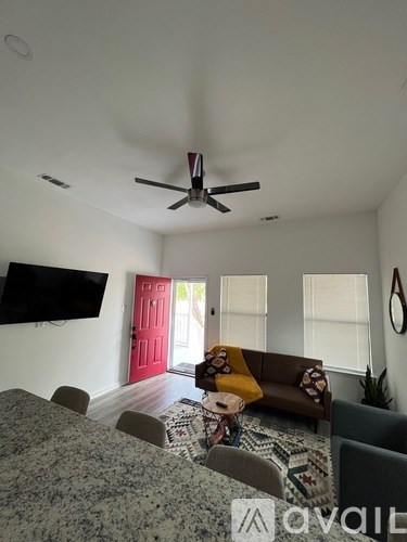A living room with a grey carpet and a brown couch.