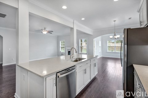 A spacious kitchen with white cabinets and a stainless steel refrigerator.