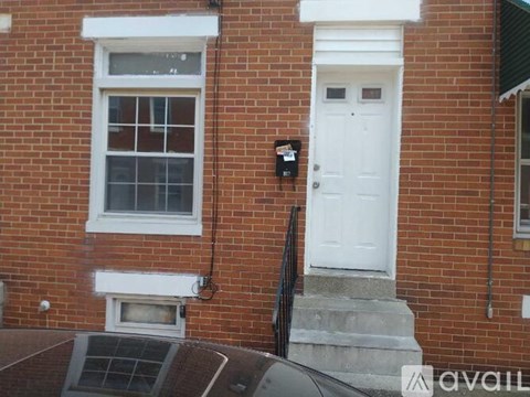 A brick house with a white door and a mailbox on the wall.