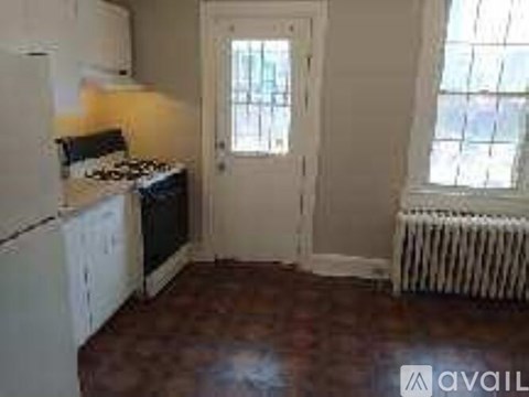 A room with a white door and a window with bars on it.