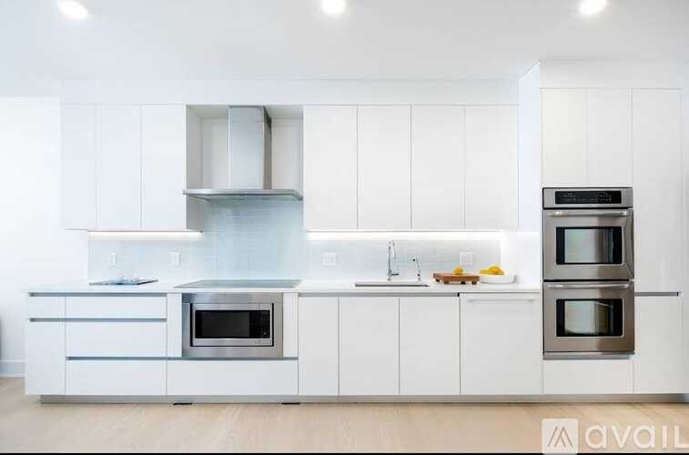 A modern kitchen with white cabinets and stainless steel appliances.