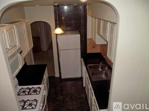 A small kitchen with a white refrigerator and black countertops.