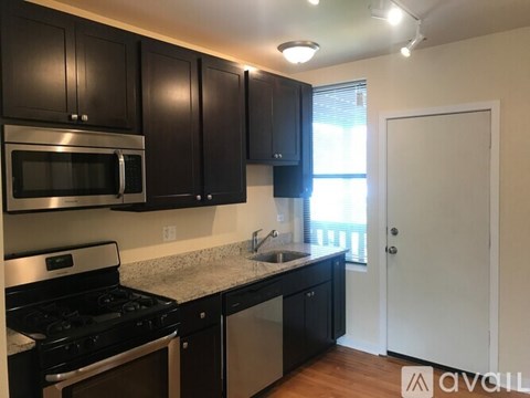 A kitchen with black cabinets and stainless steel appliances.