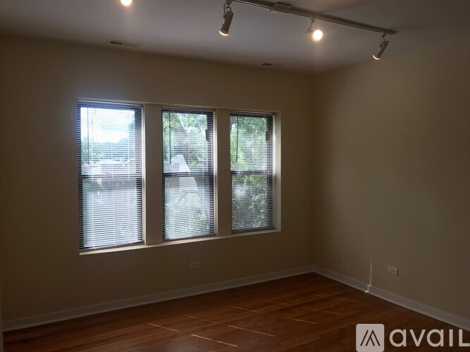A room with wooden floors and three windows.