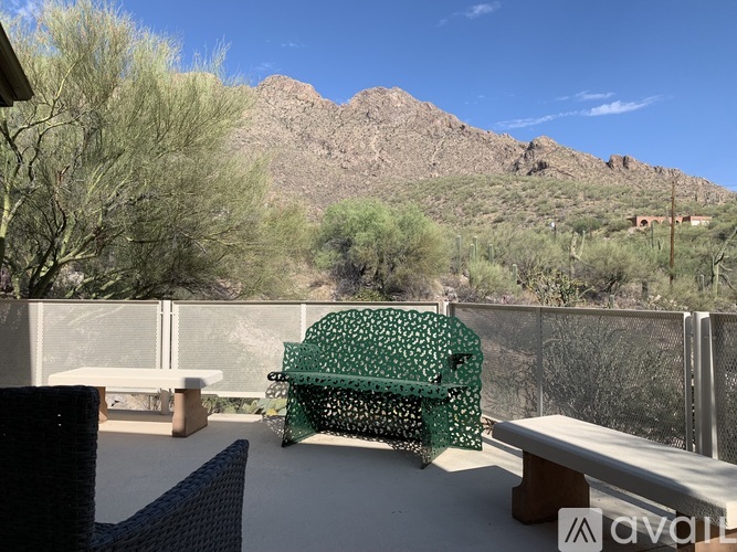 A patio with a green umbrella and a mountain in the background.