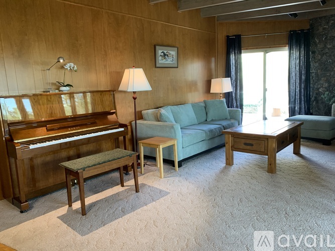 A living room with a piano, two lamps, a couch, and a coffee table.
