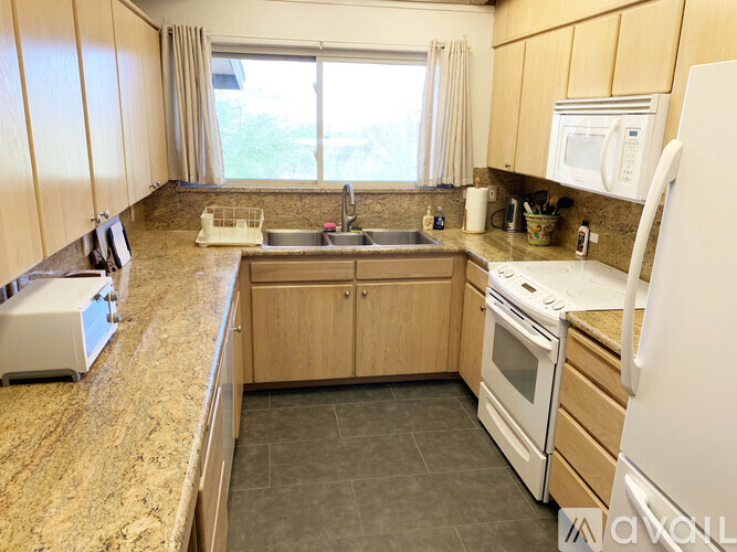 A kitchen with granite countertops and white appliances.