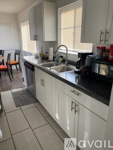 A kitchen with white cabinets and a black countertop.